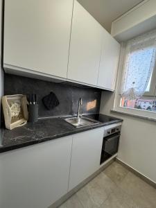 a kitchen with white cabinets and a sink and a window at Great Sweet Home in Strambino