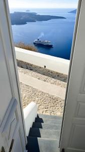 a view of a ship in the water from a door at Yposkafo Suites - Studio - Santorini in Fira