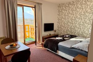 a bedroom with a bed and a table and a balcony at Apartmán Mountain View - Tatragolf C in Veľká Lomnica