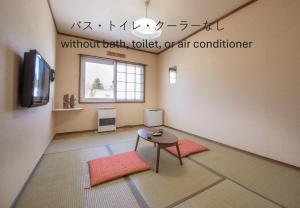 a room with two mats and a table and a tv at Shiretoko Village in Shari
