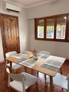 a dining room with a wooden table and white chairs at Casa Morotï - Casa de dos habitaciones en la Costanera de Corrientes in Corrientes