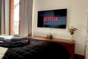 a television on a wall in a bedroom with a bed at Apartmán Mountain View - Tatragolf C in Veľká Lomnica
