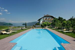 a swimming pool in front of a house at Fischerhof Agriturismo in Cornaiano