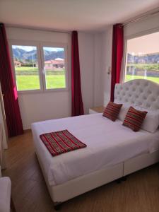 a bedroom with a large white bed with red curtains at Villa Arcadia Hotel & Eventos Cusco in Cusco