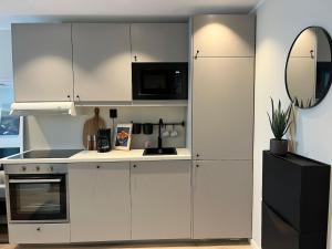a kitchen with white cabinets and a microwave at Affordable Luxury Apt - Hotel Vibe - Heart of Voss in Vossevangen