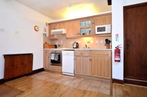 a kitchen with wooden cabinets and white appliances at Nuthatch nr Huntsham in Tiverton