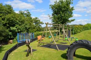 an outdoor playground with a swing set and a tire at Nuthatch nr Huntsham in Tiverton