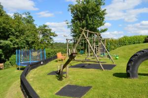 a playground with a swing set in the grass at The Long Barn nr Huntsham in Tiverton