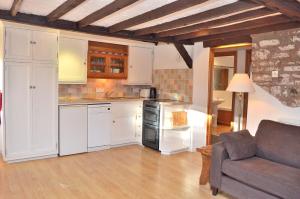 a kitchen with white cabinets and a couch in a room at The Long Barn nr Huntsham in Tiverton