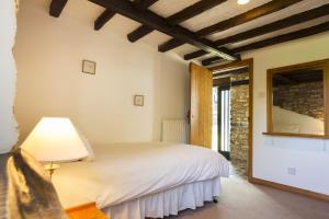 a bedroom with a bed with a lamp and a mirror at The Long Barn nr Huntsham in Tiverton +16 photos