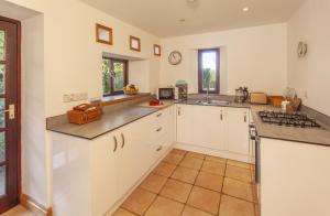 a kitchen with white cabinets and a counter top at Putham Barn Cutcombe in Wheddon Cross +13 photos