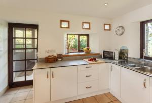 a kitchen with white cabinets and a sink at Putham Barn Cutcombe in Wheddon Cross