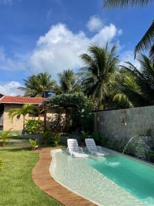 two chairs and a swimming pool in a yard at Arraia Suítes Pousada in Pipa