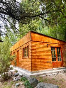 a small wooden cabin with windows in a forest at Increíble cabaña de montaña in Potrerillos