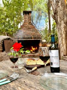 a bottle of wine and two glasses on a table with a fireplace at Increíble cabaña de montaña in Potrerillos +2 photos