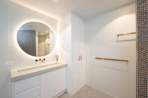 a white bathroom with a sink and a mirror at 19th Avenue on the Beach in Gold Coast