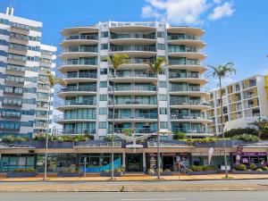 a large apartment building with palm trees in front of it at Classic Coastal Escape - 1 Bedroom Ocean Views in Maroochydore