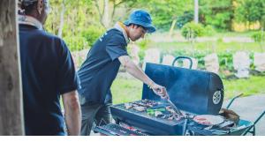 a man is cooking food on a grill at 最大8名 庭園に住むアート Active Art Hotel 80畳の広さを誇る古民家 日本庭園を独り占め in Sado