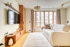 a living room with a white couch and a large window at Paris La Belle - Lafayette in Paris