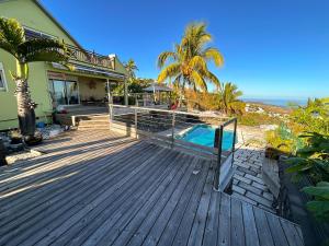 a house with a wooden deck with a swimming pool at Villa Annaga in Saint-Paul