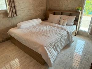 a bed with white sheets and pillows in a bedroom at Sunshine Rest Resort in Ubon Ratchathani