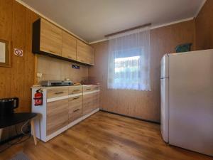 a kitchen with a white refrigerator and wooden cabinets at Domek Dębowy in Brzozie