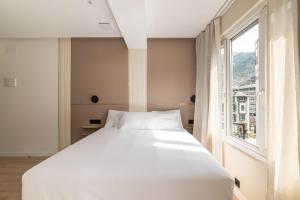 a white bed in a room with a window at LEE Hotel in Andorra la Vella