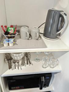 a refrigerator with a tea pot and glasses on a shelf at Small Compact Self Contained Studio Flat in Oxford +7 photos