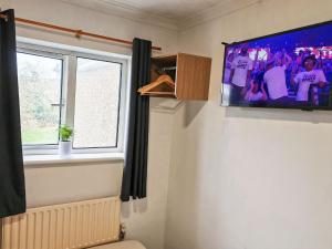 a tv on a wall in a room with a window at Small Compact Self Contained Studio Flat in Oxford