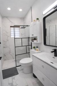 a white bathroom with a toilet and a sink at La Pergola-6 in Quebec City +2 photos