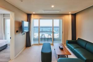 a living room with a couch and a tv at Chestertons Naksan in Yangyang