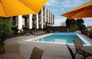 a pool with chairs and umbrellas next to a building at The Vic, an Ascend Collection Hotel in Victoria