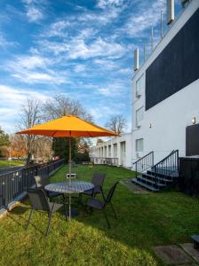 a table and chairs with an umbrella in the grass at The Vic, an Ascend Collection Hotel in Victoria