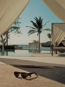 a pair of sunglasses laying on the sand near a pool at Lady D House Watamu in Watamu