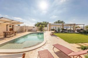 a swimming pool in a backyard with chairs and a table at Elisir Di Pace in Nardò
