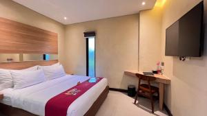 a bedroom with a bed and a desk and a television at Midtown Xpress Balikpapan in Balikpapan