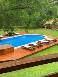 a deck with lounge chairs and a swimming pool at Buen día María Cabañas Chapadmalal in Colonia Chapadmalal
