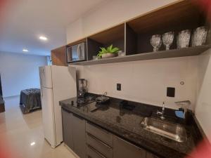 a kitchen with a black counter top and a refrigerator at Studio Proximo Anashopping Kitnet 101 in Anápolis