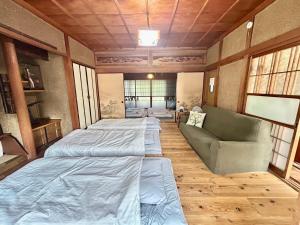 a room with three beds and a couch in it at Kominka engawa in Kakamigahara