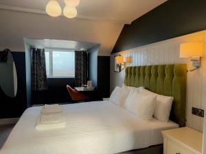ein Schlafzimmer mit einem großen weißen Bett mit grünem Kopfteil in der Unterkunft Nomi Rooms & Restaurant in Bangor