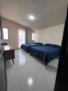 two beds in a large room with blue sheets at Casa Altita Accommodation in Zacatlán