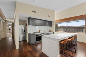 a kitchen with a counter and a kitchen island with bar stools at Kingsley in Point Lonsdale