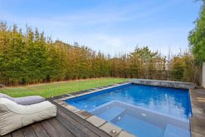 a swimming pool on a wooden deck with a chair and a couch at Kingsley in Point Lonsdale