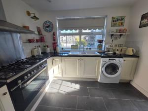 a kitchen with a sink and a washing machine at Butterlump Cottage in Glastry +36 photos