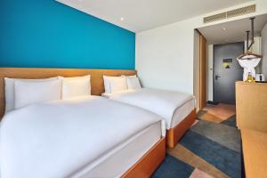 a bedroom with two beds and a blue wall at L7 HONGDAE by LOTTE HOTELS in Seoul