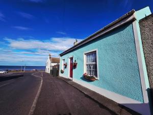 a blue building on the side of a road at Butterlump Cottage in Glastry