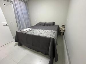 a small bedroom with a bed with a black blanket at Residenc Mazonetto in Primavera do Leste
