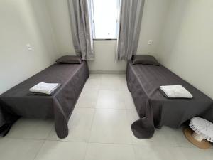 two beds in a small room with a window at Residenc Mazonetto in Primavera do Leste