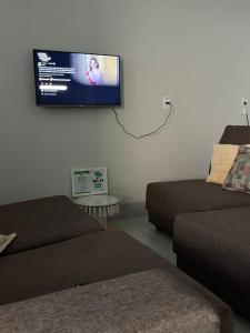 a living room with two beds and a flat screen tv on the wall at Residenc Mazonetto in Primavera do Leste