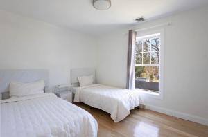 two beds in a white room with a window at Charming Home for a Perfect Escape in East Hampton